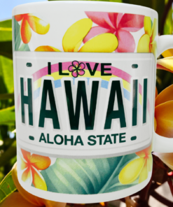 I Love Hawaii License Plate Plumeria Souvenir Mug lifestyle scene with colorful license plate artwork against yellow-orange plumeria flowers.