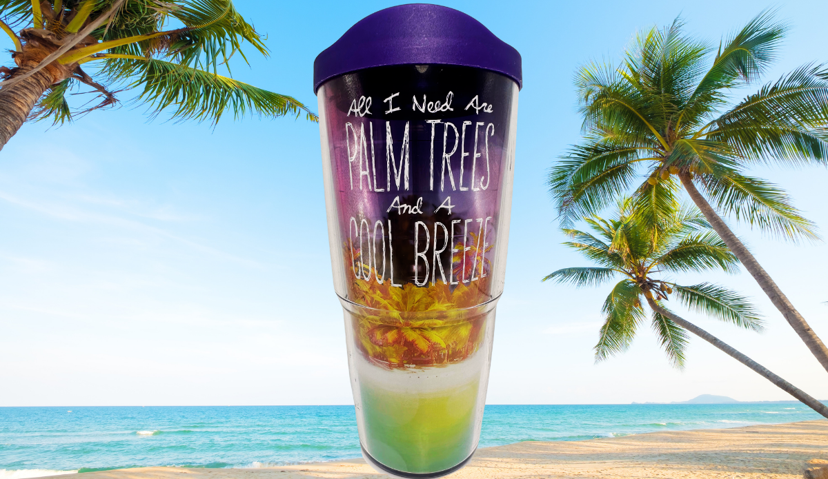 Tervis Palm Trees Cool Breeze Tumbler With purple lid displayed against a sunny tropical beach with turquoise ocean, sand, and tall palm trees.