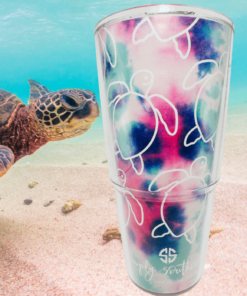 Tervis Simply Southern sea turtle tumbler displayed underwater beside a swimming sea turtle above a sandy ocean floor, with colorful tie-dye artwork.