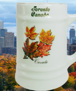 Toronto Souvenir Beer Mug lifestyle scene with colorful maple leaves displayed against Toronto skyline and autumn foliage