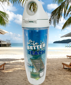 Tervis Life Is Better at the Beach Water Bottle displayed on a tropical beach with palm trees, lounge chairs, umbrellas, turquoise water, and a pier.