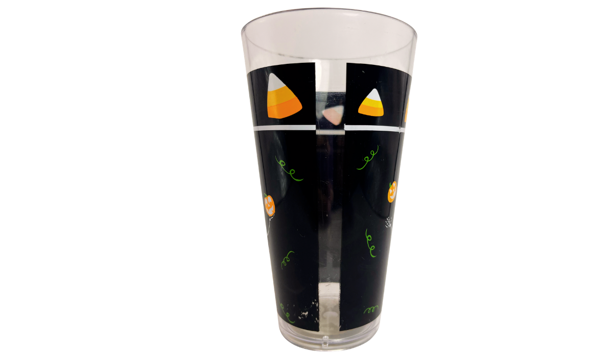 Right side view of Juggling Skeleton Halloween Acrylic Tumbler with candy corn border, black artwork, pumpkins, and green curls