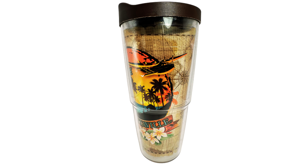 Side view of Tervis Margaritaville Island Time Tumbler With Lid showing airplane silhouette, palm trees, sunset, compass artwork, and tropical flowers.