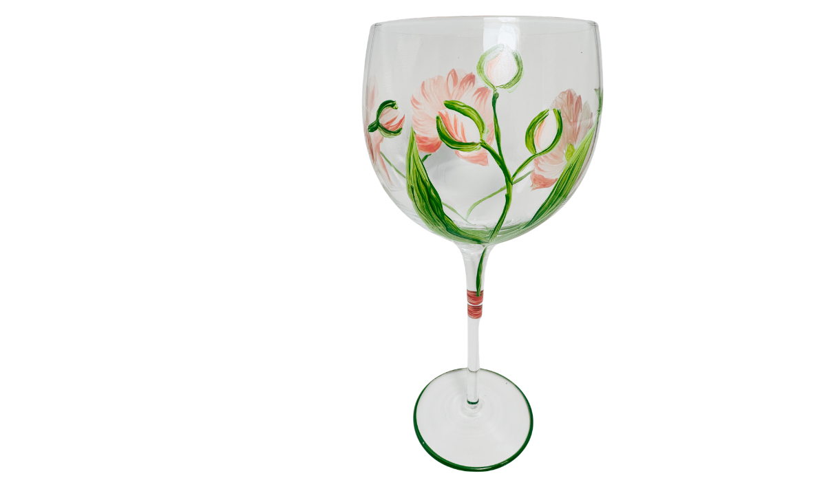 Middle view of Hand Painted White Pink Flower Balloon Wine Glass featuring pale coral blossoms, several unopened green flower buds and long painted leaves.