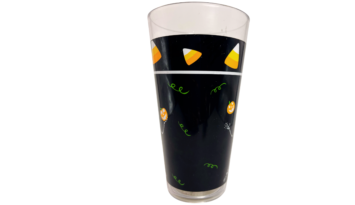 Left side view of Juggling Skeleton Halloween Acrylic Tumbler with black background, candy corn, pumpkins, and green accents