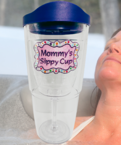 Tervis Mommy's Sippy Cup Tumbler With Lid displayed beside a woman relaxing in an outdoor hot tub, with pink emblem and purple travel lid.