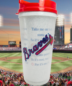 Atlanta Braves Baseball Lyrics Tumbler with red lid displayed against an Atlanta baseball stadium at sunset with cheering fans.