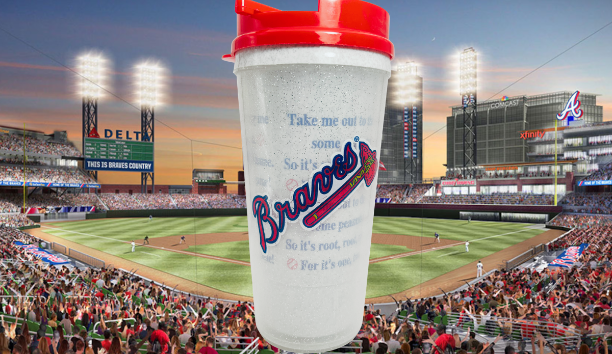 Atlanta Braves Baseball Lyrics Tumbler with red lid displayed against an Atlanta baseball stadium at sunset with cheering fans.