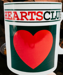Hearts Playing Cards Coffee Mug displayed at a game-night table with playing cards, a wooden stacking game, and people gathered around.