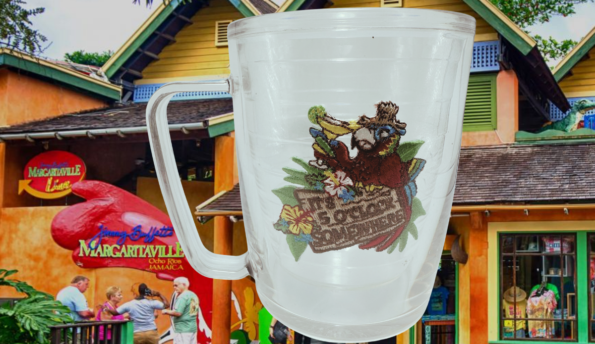 Tervis Margaritaville Red Parrot Mug displayed against Jimmy Buffett's Margaritaville in Ocho Rios, Jamaica, with colorful tropical buildings and signage.