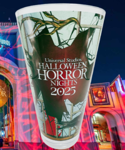 Halloween Horror Nights 2025 Souvenir Cup displayed in front of the illuminated Universal Studios entrance at night