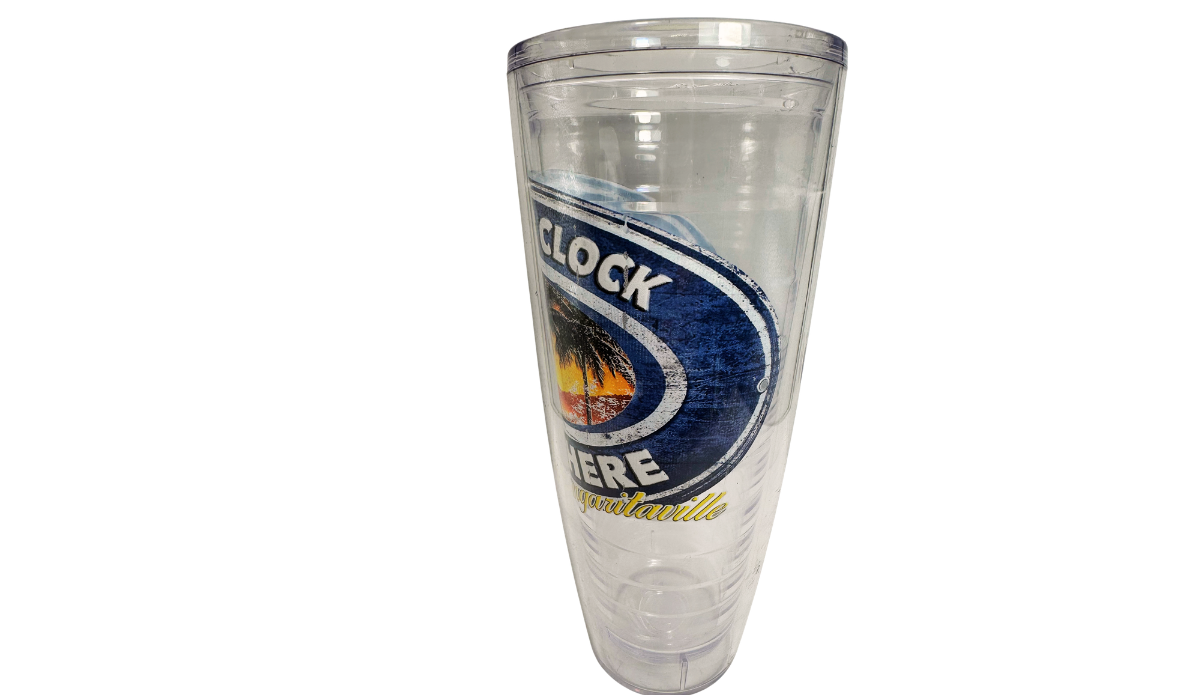 Right side view of clear Margaritaville sunset tumbler showing curved navy-blue border, partial clock lettering, sunset artwork, and yellow Margaritaville script.